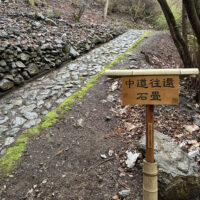 裏にQRコード付看板：2026年4月の再訪時の写真：最初の調査時（2023年）よりも掘り出された石畳の長さが上の方へ5倍くらい伸びていた。