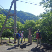 籠の渡しの解説板を見る。張られたワイヤーには昔の籠の模型が川面に下がっている
