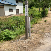 舗装道路から朴の木峠への案内標柱。民家の脇を入っていく
