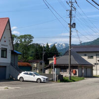 萱野峠への案内標柱　遠くに見えるのは飯豊連峰