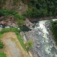 かつて戸下温泉があった黒川と白川の合流点：阿蘇山麓温泉として一世を風靡した戸下温泉であるが、立野ダムの計画に伴い閉鎖され今は更地となり長陽大橋の橋脚が立つ。黒川の流れが白川の流れにＴ字形にぶつかる ように合流している。合流点には熊本地震で崩落した岩が半ば白川の流れを塞いでいる。(長陽大橋から)
