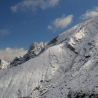 白銀の高岳北稜の仙酔尾根と鷲ヶ峰・虎ヶ峰：高岳の登山口仙酔峡はミヤマキリシマの名所としても知られ、春5月、ロッククライミングの殿堂である鷲ヶ峰、虎ヶ峰を背にして、花と岩峰の競演は圧巻であり、絶景は多くの人を魅了する。(中央の稜線が仙酔尾根、奥が鷲ヶ峰(右)と虎ヶ峰(左))